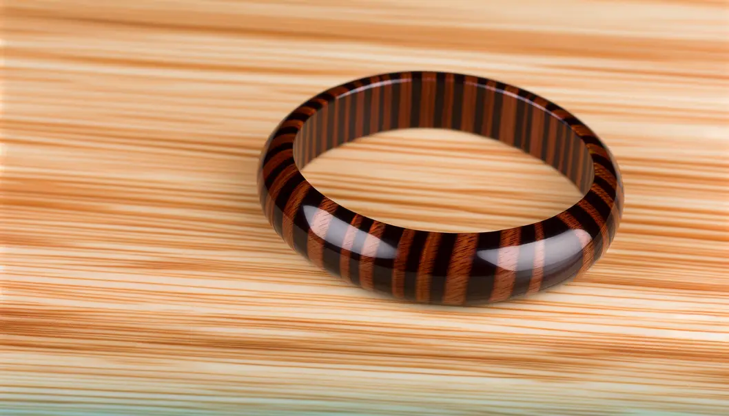 Chiếc vòng tay gỗ mun sọc sang trọng nằm trên nền gỗ tự nhiên.